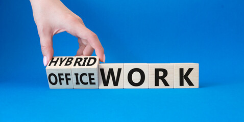 Hybrid work and office work symbol. Businessman hand turns wooden cubes and changes words Office work to Hybrid work. Beautiful blue background. Business and success concept. Copy space