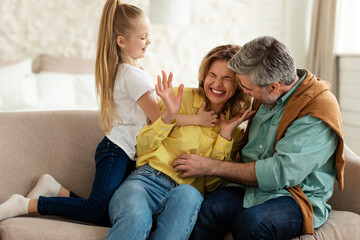 Family Having Fun Tickling And Cuddling Sitting At Home