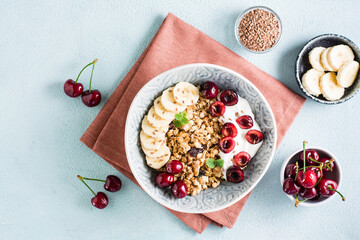 Granola with cherry, banana and flax seeds in a bowl on the table. Homemade breakfast. Top view