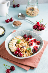 Granola with cherry, banana and flax seeds in a bowl on the table. Homemade breakfast. Vertical view