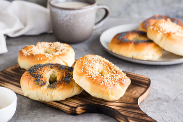 Obraz na płótnie Canvas Bagels with poppy seeds and sesame seeds on a plate and a cup of coffee. Homemade breakfast.