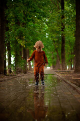 a little boy runs and jumps in the puddles during the summer rain.Childhood.