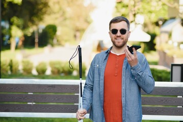 Young blinded man using phone and sending voice message