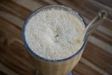 Vanille Milch-Shake im Glas auf braunem Tisch mit Muster in Café 