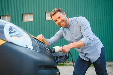Obraz premium Man charging his electric car at charge station.