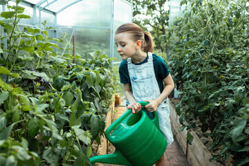A girl watering plants in a greenhouse