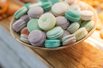 macarons of different colors in a wooden plate on the table