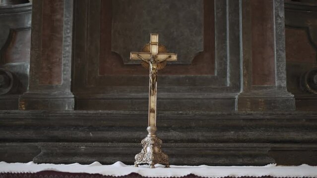 Metal Cross Depicting The Crucifixion Of Jesus Christ And Adam Head, Death Head On Rich Bronze Stand Stands On White Tablecloth On An Ancient Old Altar, Close-up.