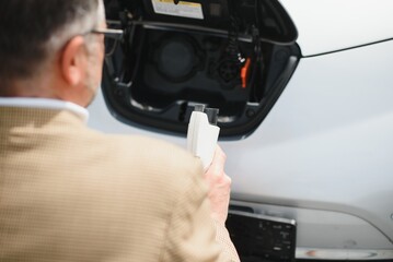 Man holding power connector for electric car