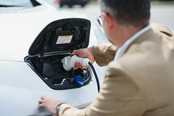 Man holding power connector for electric car