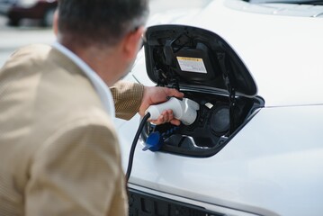 Fototapeta premium Man holding power connector for electric car