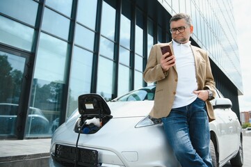 a businessman charges an electric car