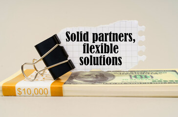 There are dollars on the table, on which there is a clip and torn paper with the inscription - Solid partners