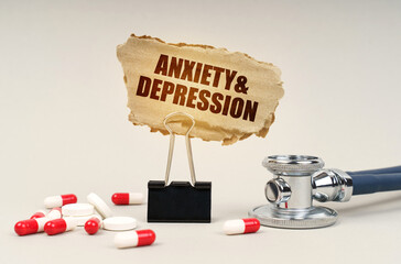 Near the stethoscope are pills and a clip with a cardboard sign - Anxiety and Depression