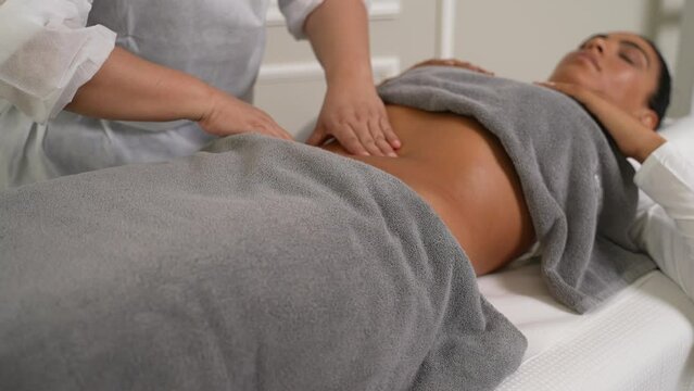 massage therapist doing a belly massage to a slim woman