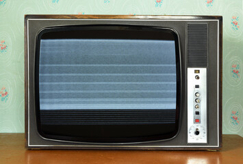 Old vintage TV with screen noise in a room with vintage wallpaper. Interior in the style of the...