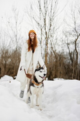 Fototapeta na wymiar Happy young woman in the snow playing with a dog fun friendship fresh air