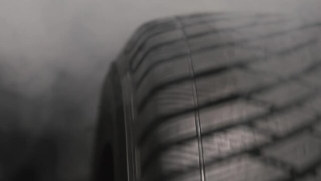 Smoking Tire in a Drift. The spinning wheel rubs against the asphalt and creates a cloud of white smoke on a black background. Filmed at a speed of 120fps