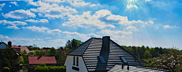 Błękitne niebo z chmurkami ponad dachami miejskich domów .