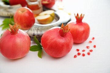 Pomegranates and red apples on white background, traditional food of jewish New Year - Rosh...