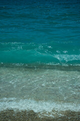 Sea wave with foam. Blue background. Vertical image. Copy space. Travel and wellness concept