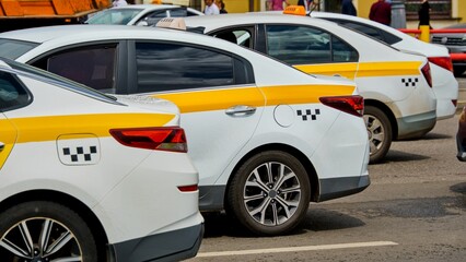 White and yellow taxis stand in a tight traffic jam on a hot sunny day. Synchronous arrangement of...