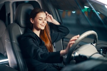 Plakat a happy, relaxed woman enjoys a night drive while sitting in a car and holding her hand near her head in a relaxed pose