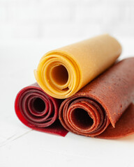 Fototapeta na wymiar Pastille rolls. Fruit leather in slices (pastila). Raw food, vegan sweetness, dessert without sugar and flour. For text and articles on healthy eating.Colorful fruit leather rolls on light background.