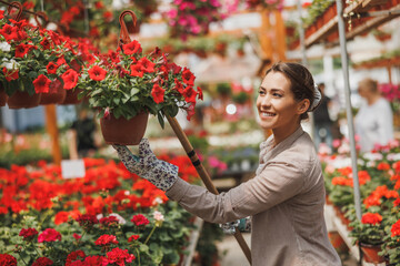 Woman Working In Plant Nursery And Taking Care Of Potted Plants