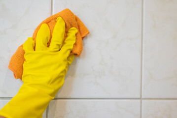 girl in rubber gloves with a rag cleans the bathroom
