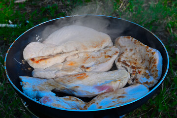 Roast turkey meat in a pan in the woods while camping