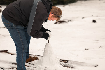 Man biulding snow man. Winter in Australia