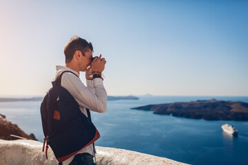 Santorini traveler man taking photo of Caldera from Fira or Thera, Greece on camera. Tourism,...