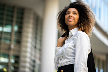 Confident young afro american female manager outdoor in a modern urban setting holding her jacket