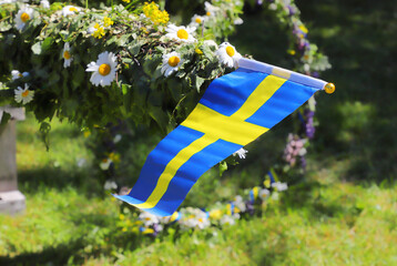 Traditional midsummer pole with Swedish flag awaits the rising ceremony. - obrazy, fototapety, plakaty
