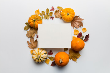 Autumn composition with paper blank and dried leaves with pumpkin on table. Flat lay, top view, copy space