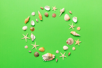 Summer time concept on colored background. Seashells from ocean shore in the shape of frame separated with space for text top view