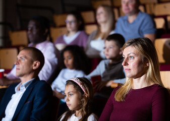 Young woman spending time with her family, watching together interesting movie in picture theater
