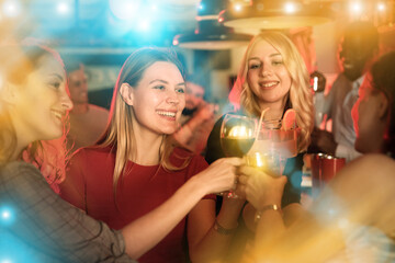 Female friends enjoying wine in night club. High quality photo - obrazy, fototapety, plakaty