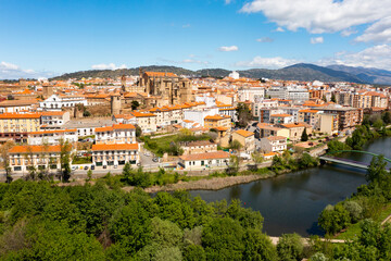Picturesque aerial view of Plasencia city located in valley of Jerte river overlooking terracotta tiled roofs of residential buildings and medieval cathedral complex in spring, Extremadura, Spain