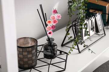Reed diffuser with flying flowers on shelf in room