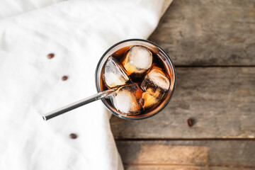 Glass of cold brew with straw on wooden table