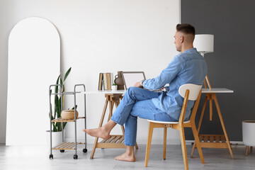Young barefoot man using laptop at home