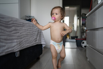 One female toddler caucasian in diapers running in the house Early child development learning and...