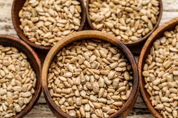 Bowls with peeled sunflower seeds on white wooden background, closeup