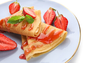Plate of thin pancakes with strawberries and mint leaves on white background, closeup