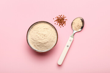 Fototapeta premium Bowl of flour, spoon and buckwheat grains on pink background