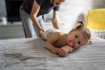 Father changing diapers his daughter toddler girl at home in bedroom Early development and parenting concept - obrazy, fototapety, plakaty