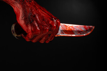 A man with bloody hands brandishes a knife on a black background. 