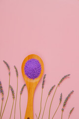 lavender salt in wooden spoon and lavender flowers on a pink background.purple sea bath salt . Flower bath salt.Aromatherapy and spa.body cosmetic with lavender extract.